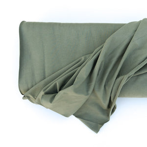 Elvelyckan Green Organic Cotton Jersey Rib Fabric. Fabric is on a roll with a white background