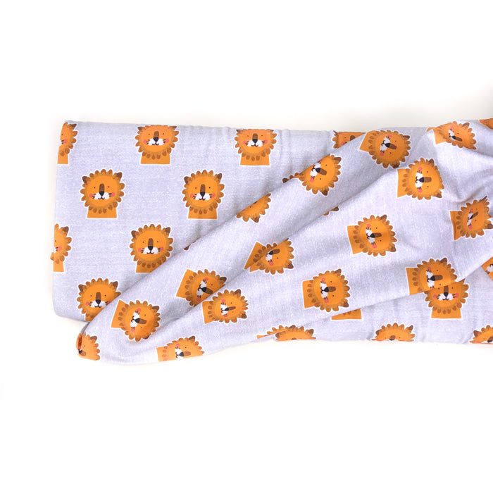 Stock photo of Lillestoff organic jersey knit fabric in Mr Leo design. Pale grey background with yellow/orange lion faces