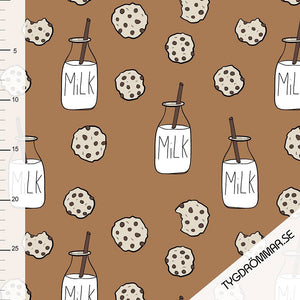 Stock photo of Tygdrommar Milk N Cookie Light Pink Organic Cotton Jersey Knit Fabric. The fabric has images of chocolate chip cookies and bottles of milk on a sandstorm brown background.