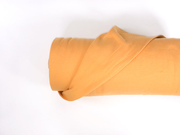 Photo of a roll of Lillestoff organic cotton jersey ribbing in the colour ochre.