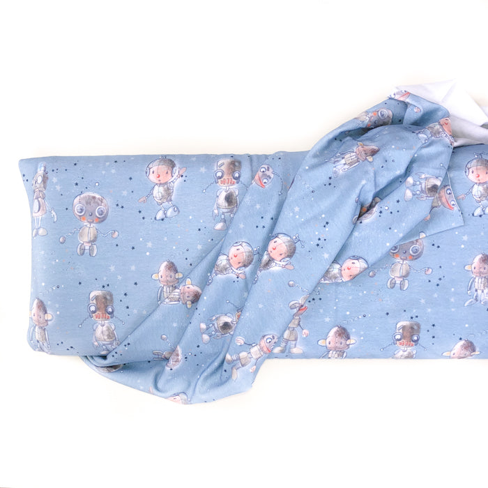 Stock image of Lillestoff Robbi and Co Organic cotton jersey knit. Fabric has blue background with little blue and white starts and cute little cartoon robots on it.