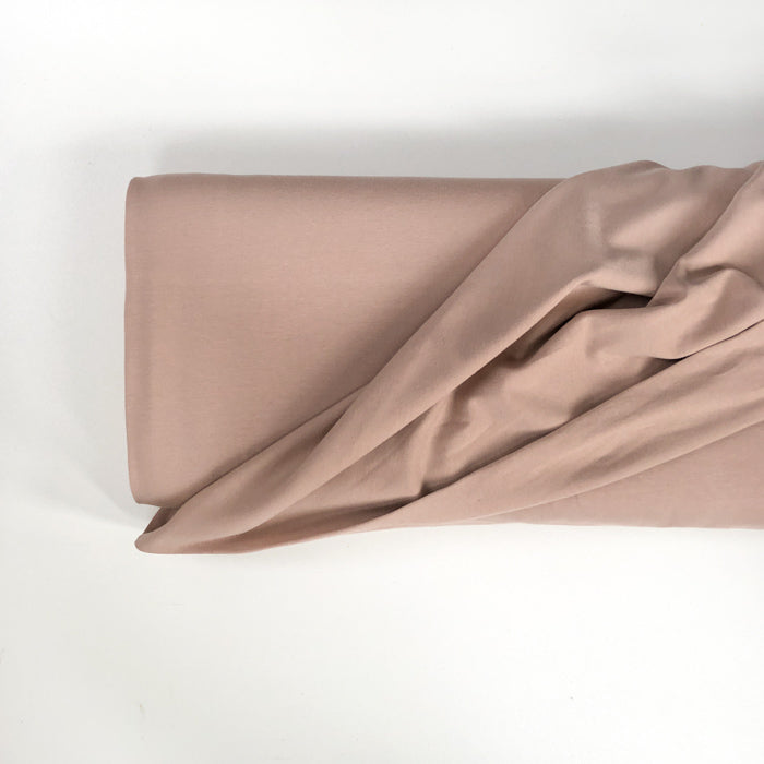 A roll of Family Fabrics Cotton Jersey knit in the shade Roebuck. A light brown/tan colour.